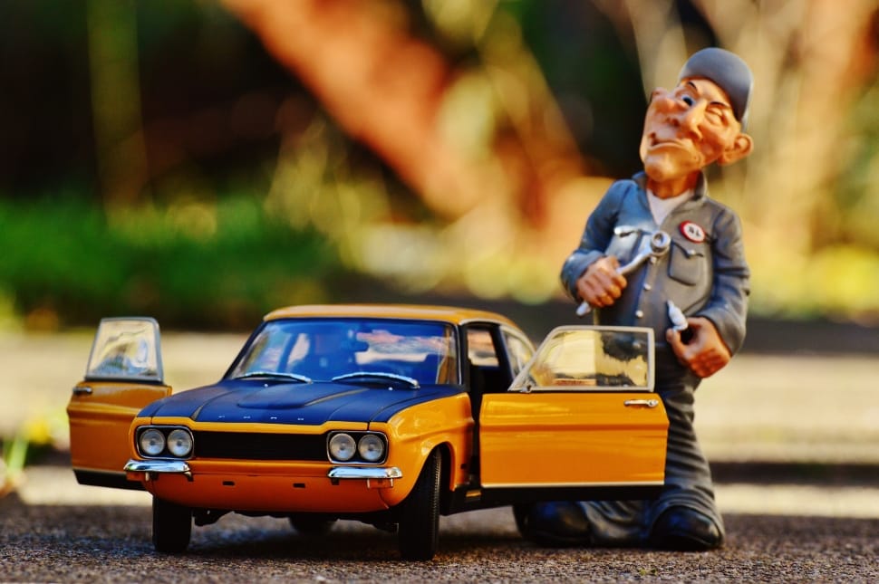 yellow and blue car scale model and man in grey suit figurine preview