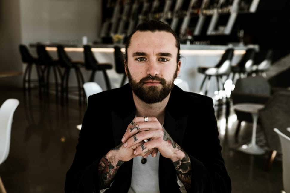 man in black blazer with short beard on other side on table preview