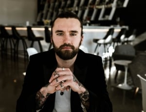man in black blazer with short beard on other side on table thumbnail