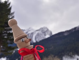 brown wooden character figurine with white snow cop in background thumbnail