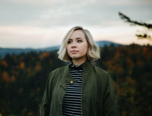 woman wearing green jacket standing on highlands during golden hour thumbnail