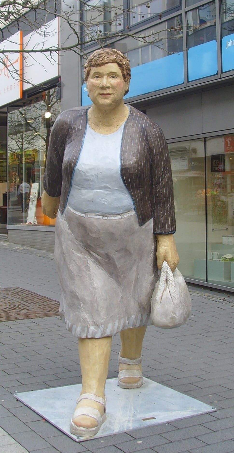 mother in blue and gray dress with brown blazer holding white handbag statue preview