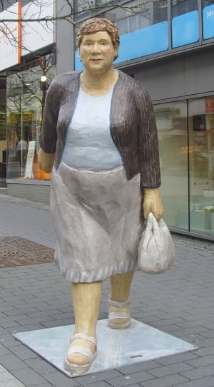 mother in blue and gray dress with brown blazer holding white handbag statue thumbnail