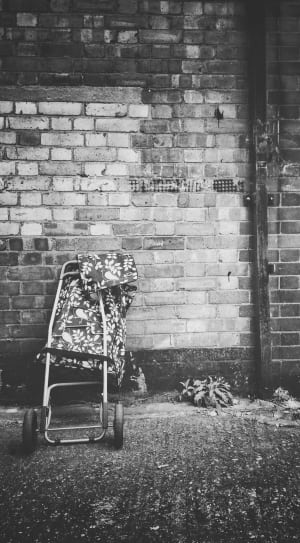 baby's lightweight stroller in front of brick wall in grayscale photography thumbnail