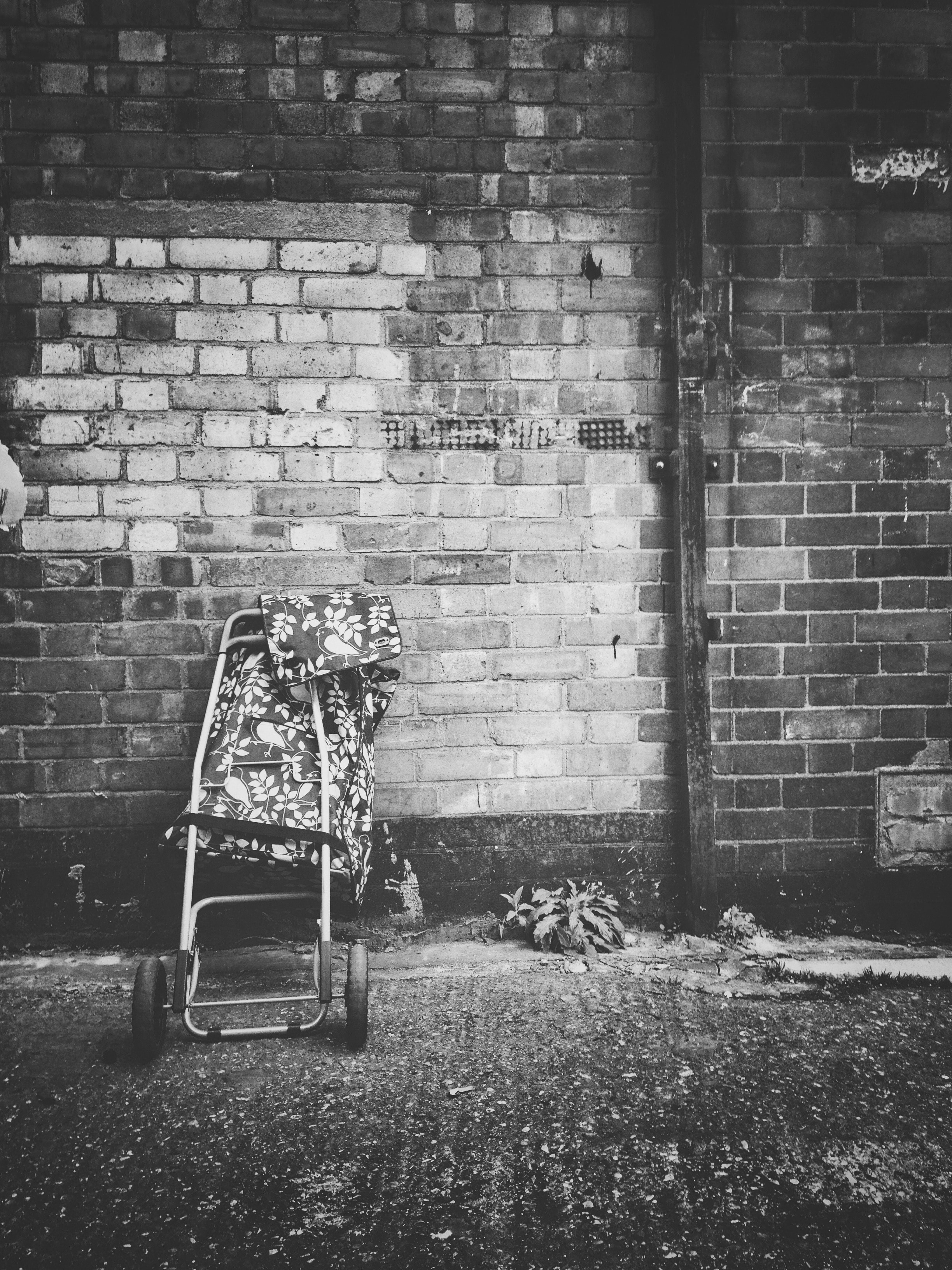 baby's lightweight stroller in front of brick wall in grayscale photography