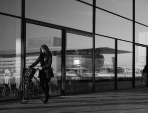 woman in coat with bicycle near a mirror wallet building thumbnail
