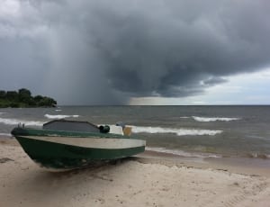 green and white motor boat beside sea during stormy season thumbnail