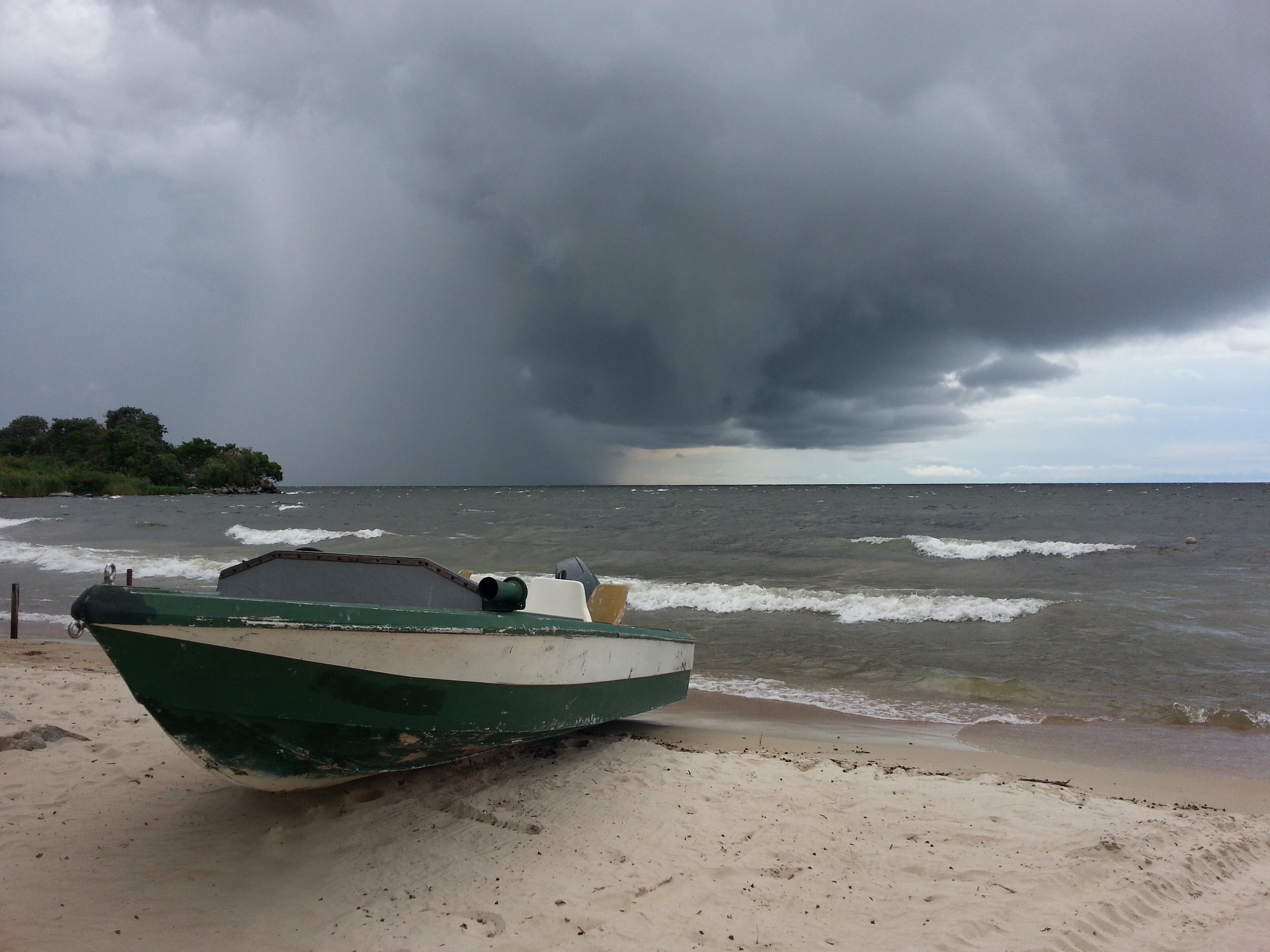 green and white motor boat beside sea during stormy season
