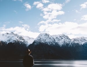 person wearing hat and shirt while facing mountains thumbnail