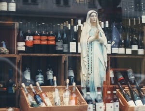 virgin mary figurine in the middle of bottles thumbnail