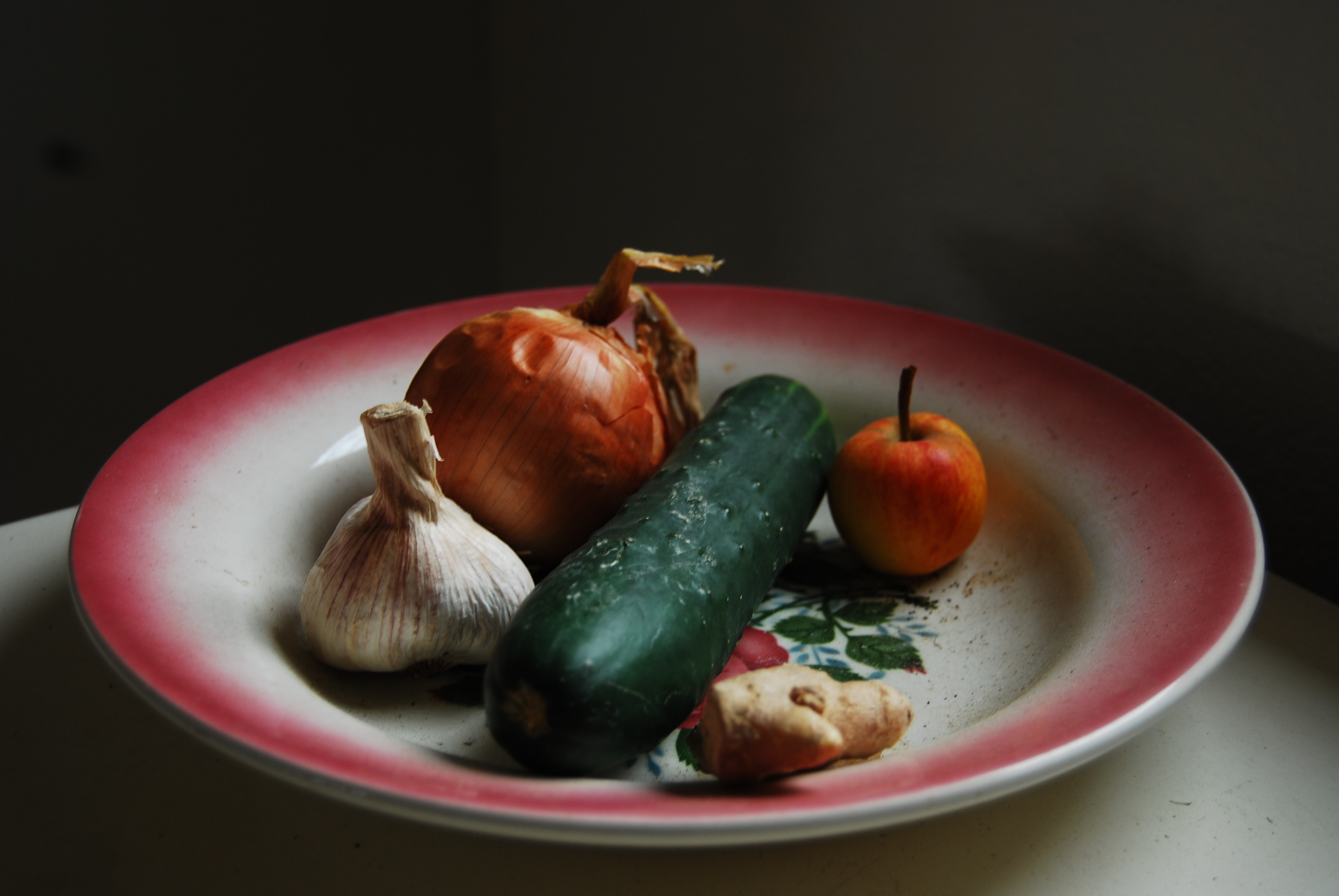 cucumber, garlic, and union on white-and-red ceramic plate