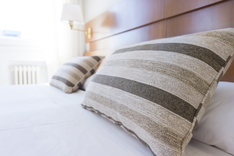 two green and white stripe print throw pillows and white bed sheet preview