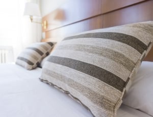 two green and white stripe print throw pillows and white bed sheet thumbnail