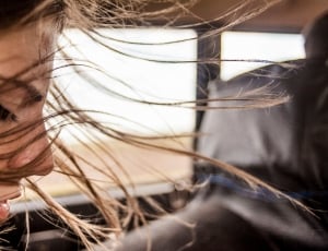 woman sitting inside vehicle with hair on face during daytime thumbnail