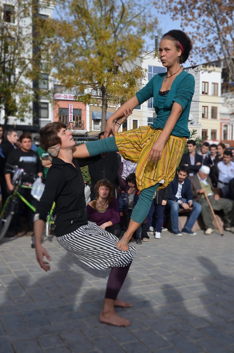 woman standing on one foot on man's lap and the other foot on the neck ...