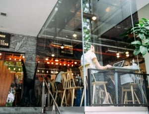 person sitting on beige chair in front of laptop in glass building during daytime thumbnail
