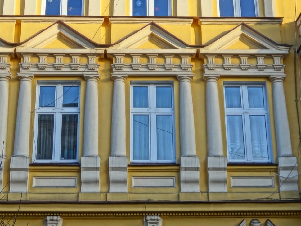 three rectangular white metal framed windowpanes on yellow painted building preview