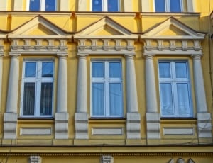 three rectangular white metal framed windowpanes on yellow painted building thumbnail