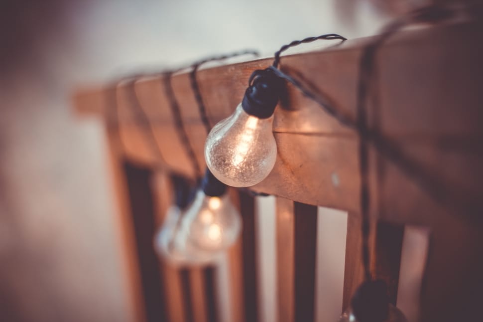 selective blurry photography of string lights on brown wooden fence preview