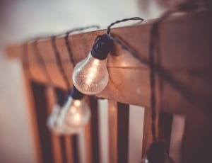 selective blurry photography of string lights on brown wooden fence thumbnail