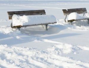 two brown steel benches filled with snows thumbnail