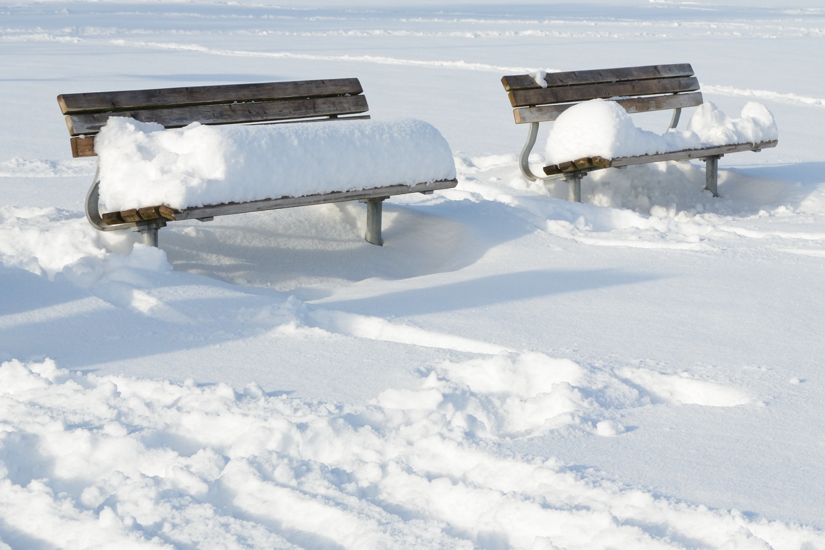 two brown steel benches filled with snows
