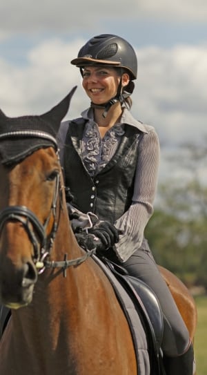 woman in grey black long sleeve shirt riding on brown horse thumbnail