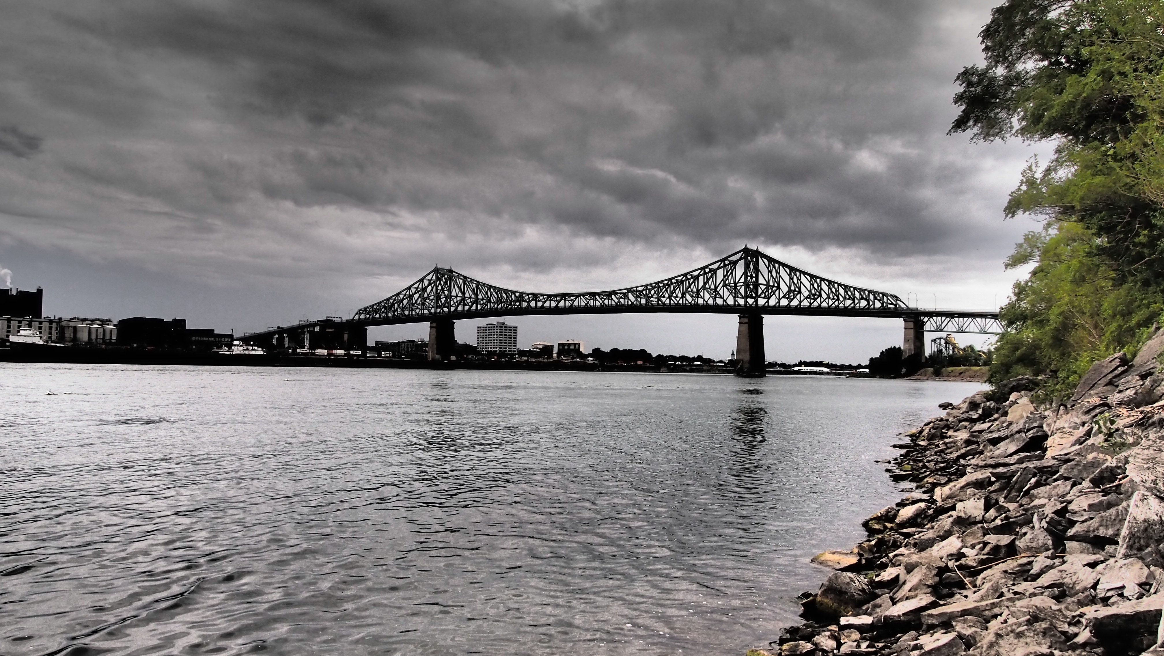 gray bridge above body of water under gray clouds during daytime photo