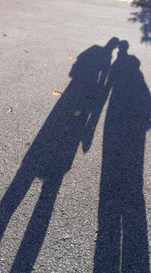 shadow of 2 person on asphalt road during daytime thumbnail