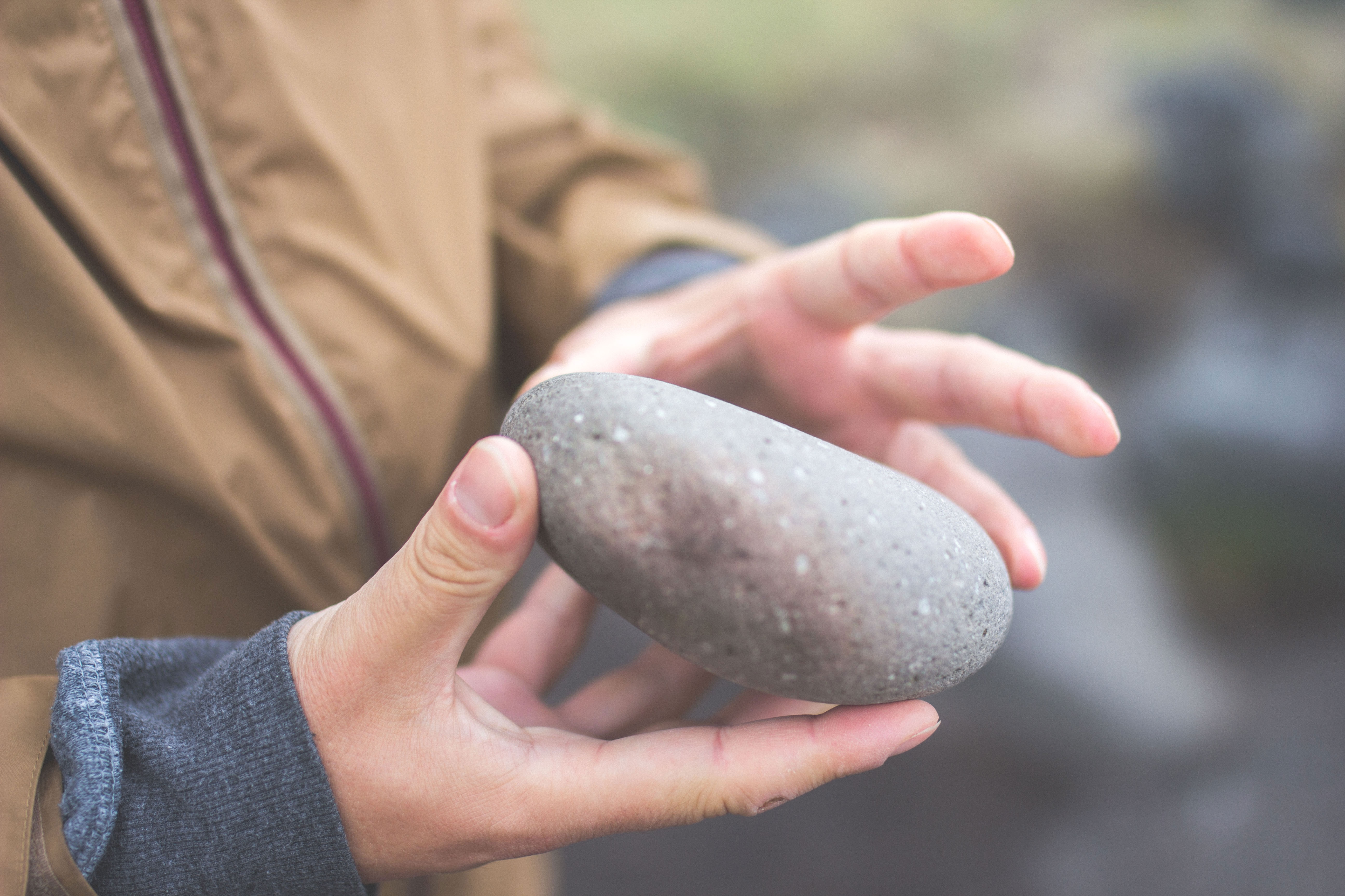 human holding round gray stone