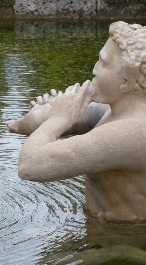 man sculpture on body of water thumbnail