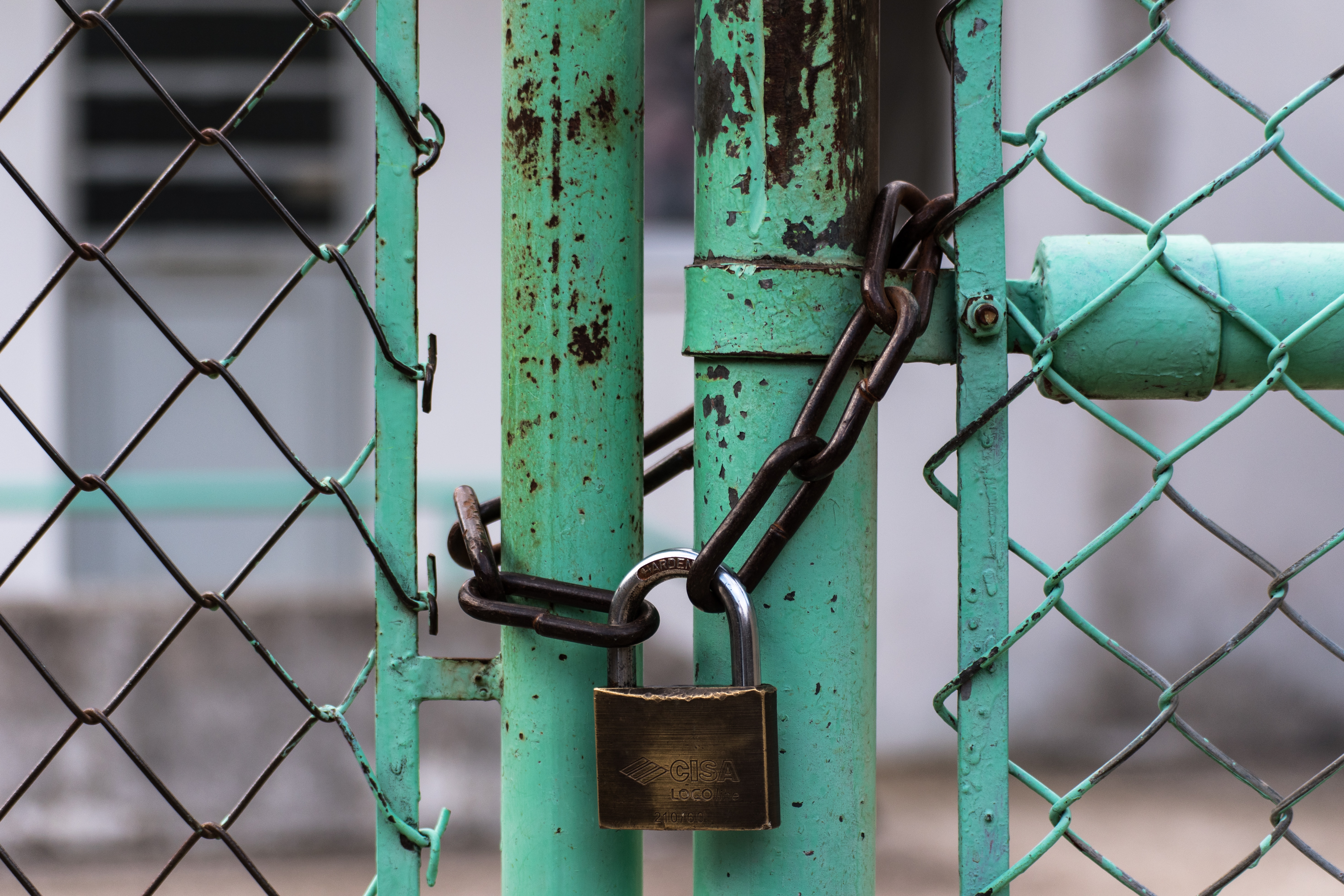 brown padlock on teal steel gate
