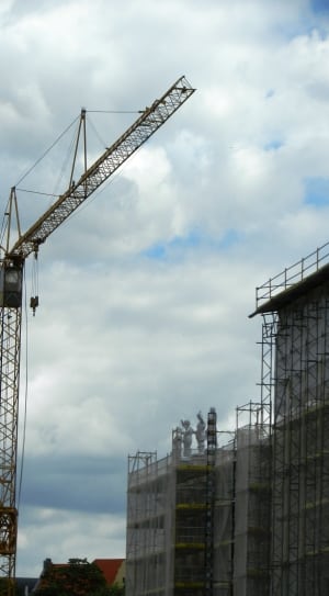 black crane near concrete building under cloudy sky at daytime thumbnail