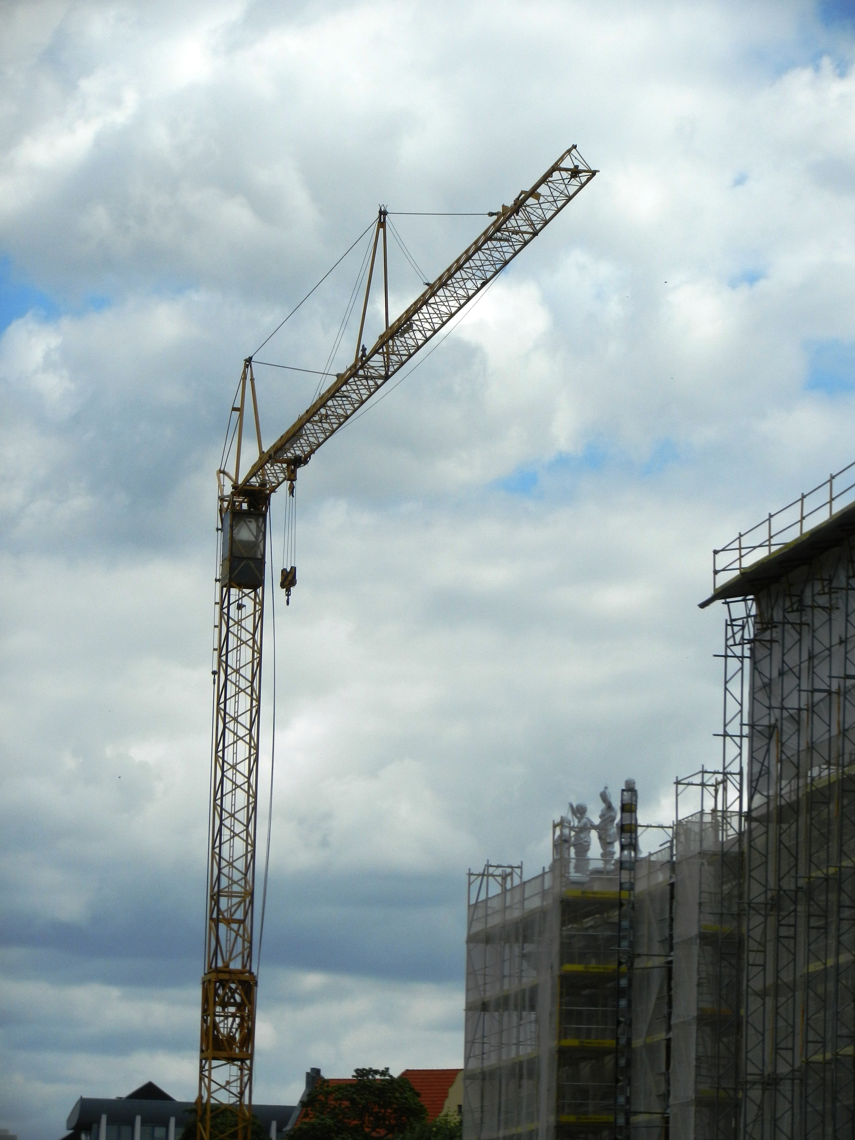 black crane near concrete building under cloudy sky at daytime