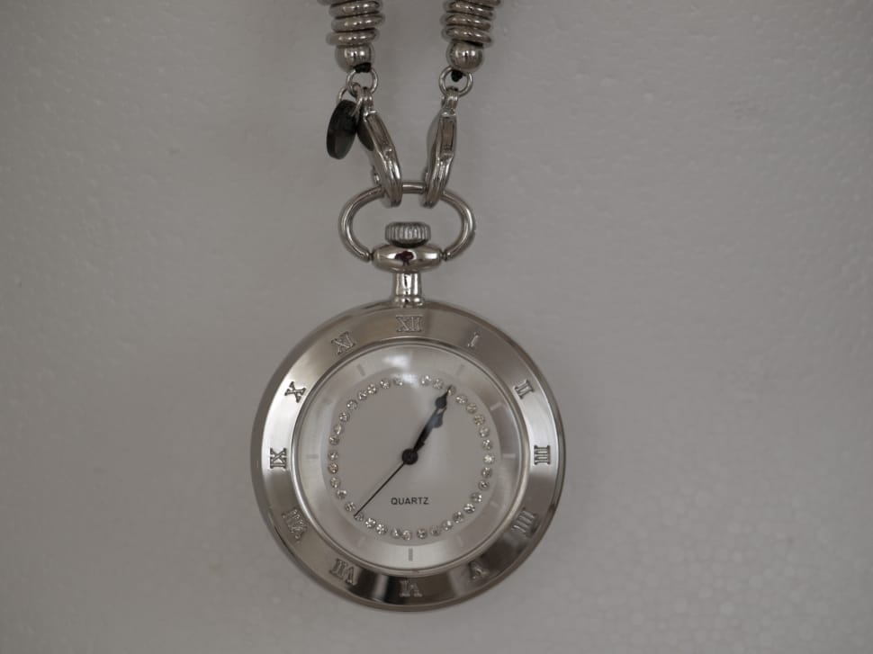 silver link chain pocket watch on top of white surface preview