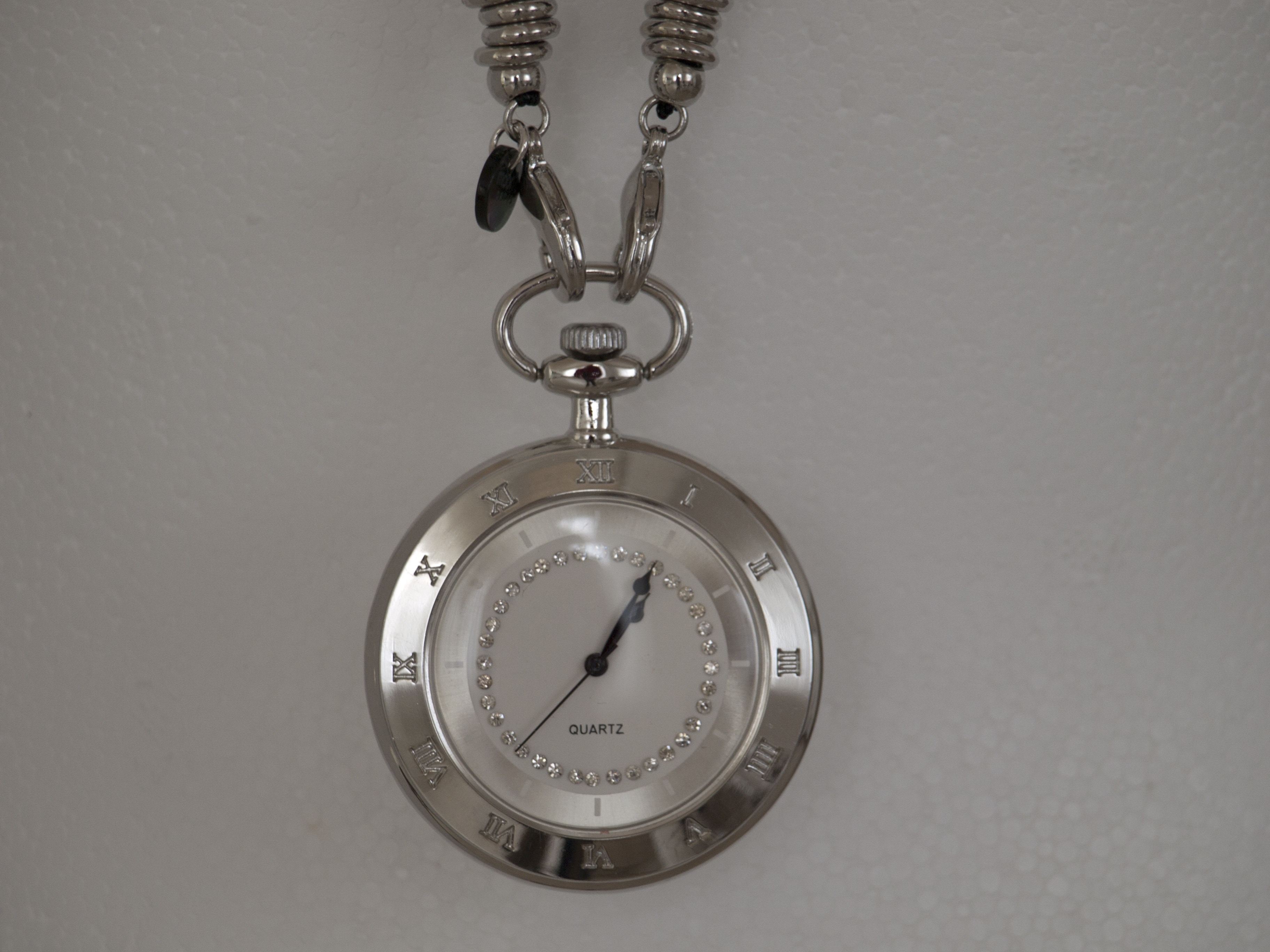 silver link chain pocket watch on top of white surface