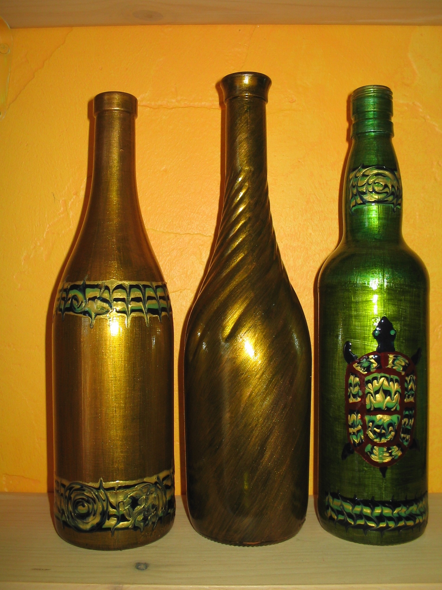 2 gold glass bottles and green glass bottle