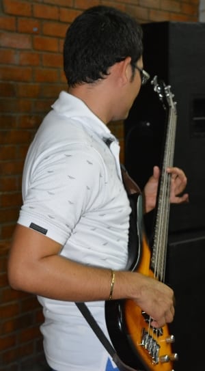 men's white and black polo shirt and sunburst electric bass guitar thumbnail