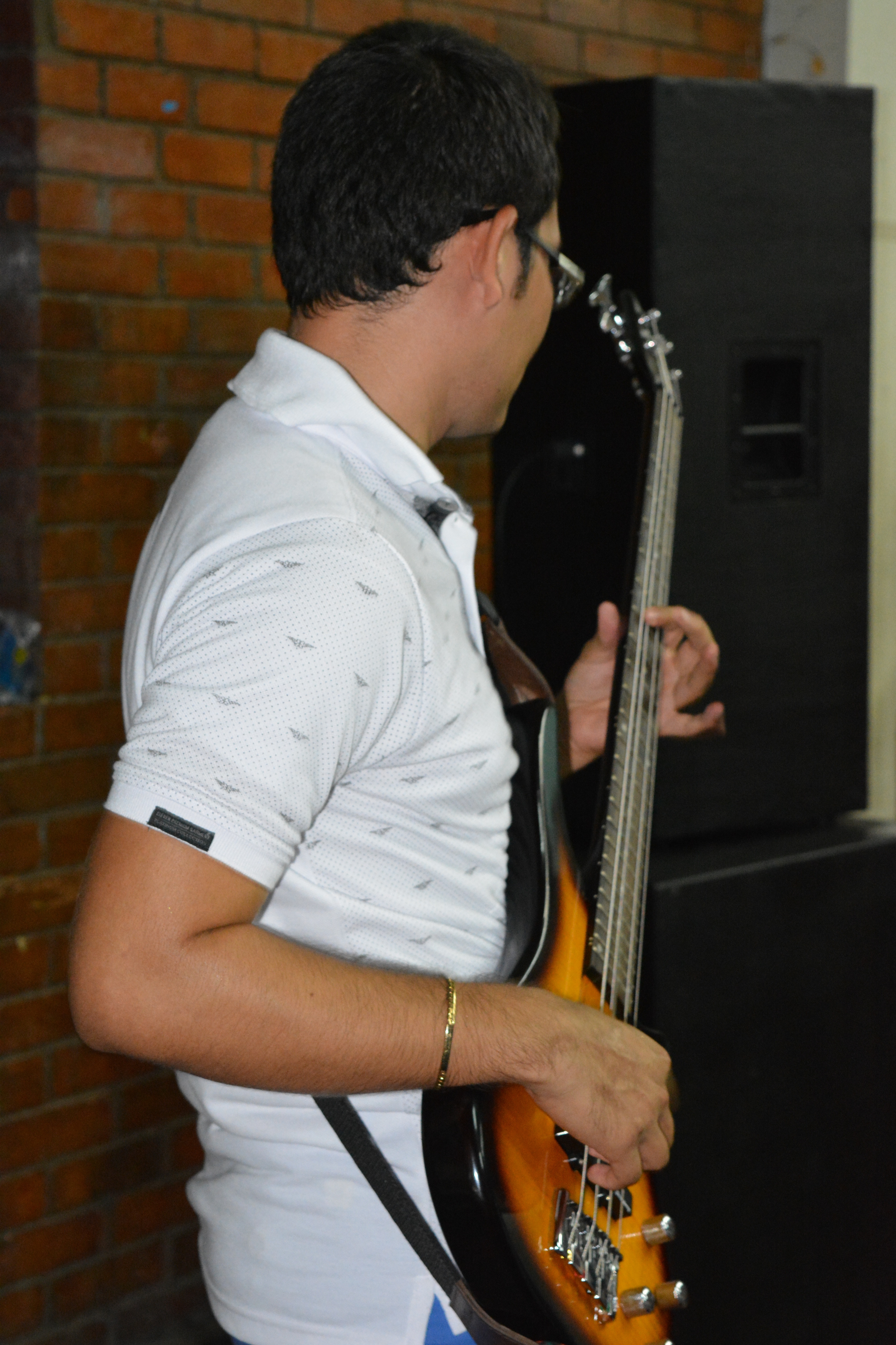 men's white and black polo shirt and sunburst electric bass guitar