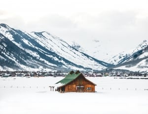 brown house near mountain covered in snow thumbnail