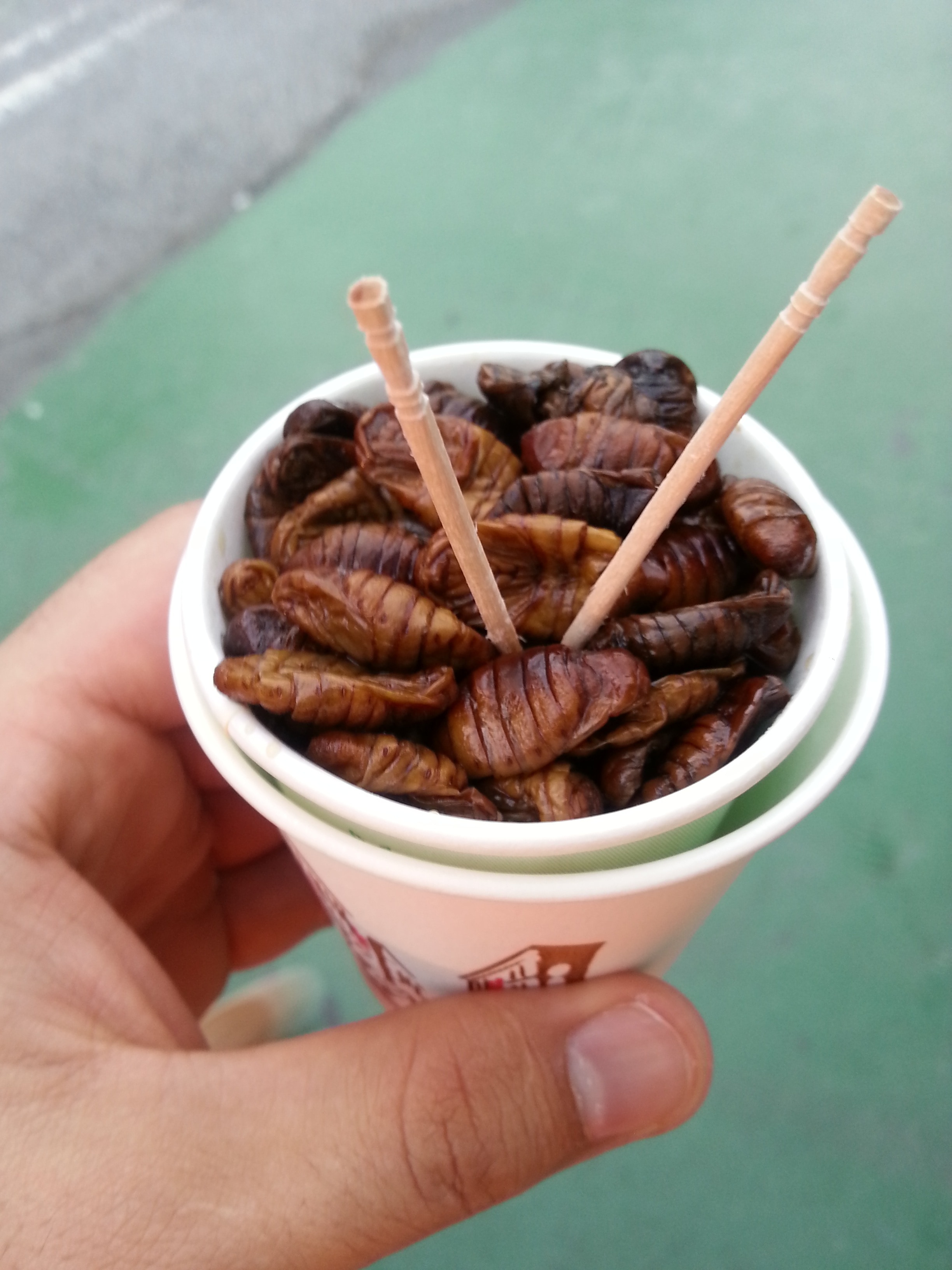 two toothpicks on brown food in white plastic cup