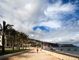 woman walking on pathway near ocean thumbnail
