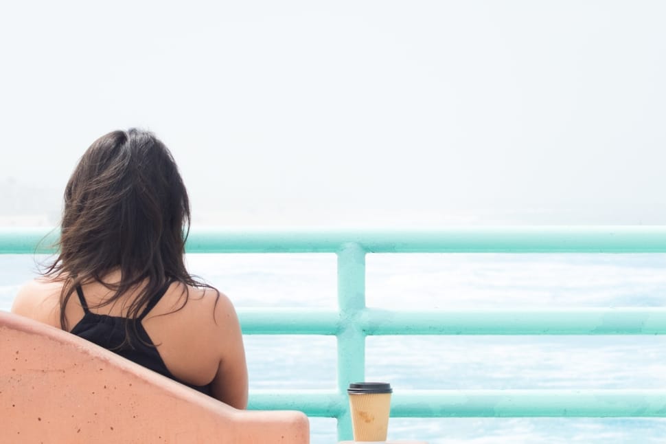 woman sitting near ocean during daytime preview