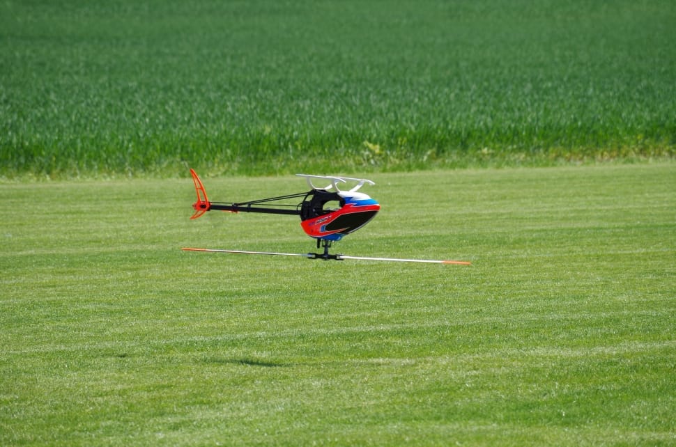 red, black and blue rc helicopter flying above green grass field during daytime preview