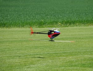red, black and blue rc helicopter flying above green grass field during daytime thumbnail