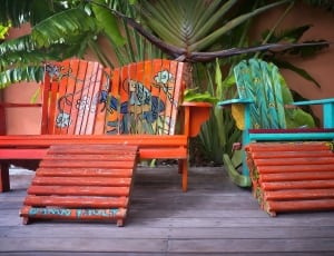 orange wooden lawn bench and teal cyan and green rocking chair thumbnail