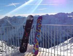2 purple and black snowboard and snow capped mountain thumbnail