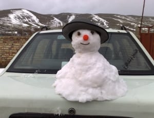 white snow man on top of white sedan thumbnail