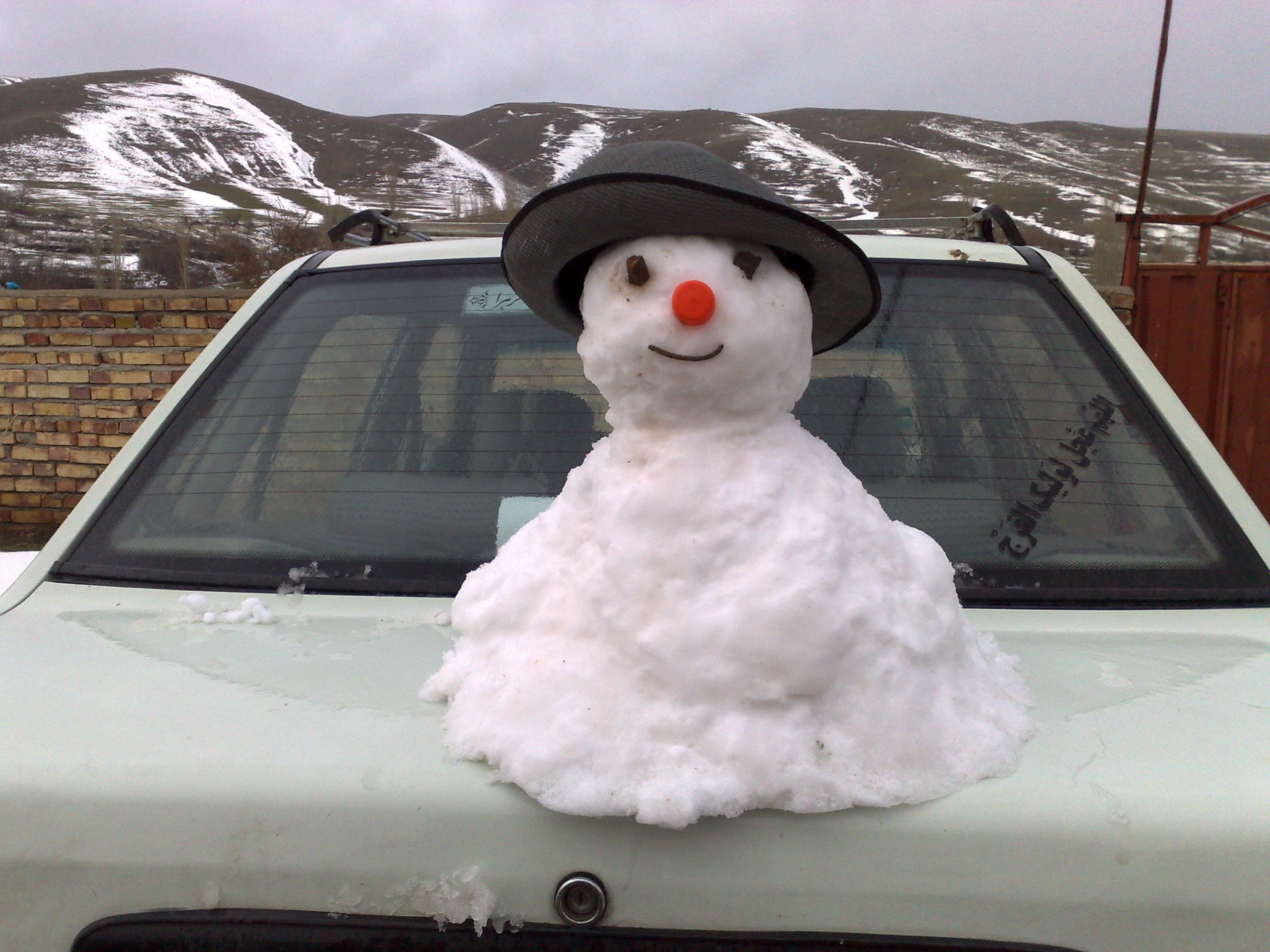 white snow man on top of white sedan