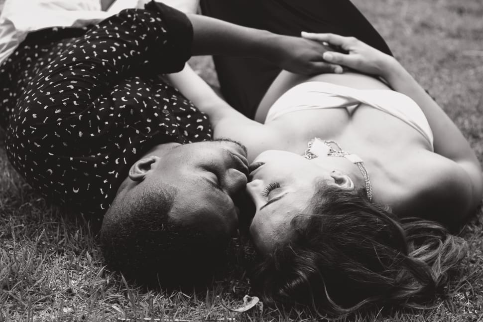 gryscale photo of couple lying on grass field preview